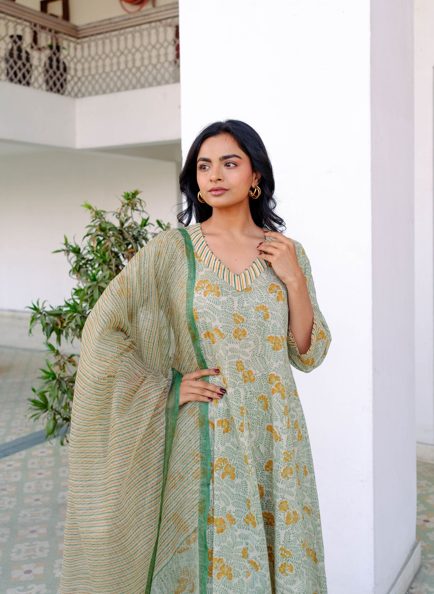 Woman wearing a green and gold traditional outfit with a white background