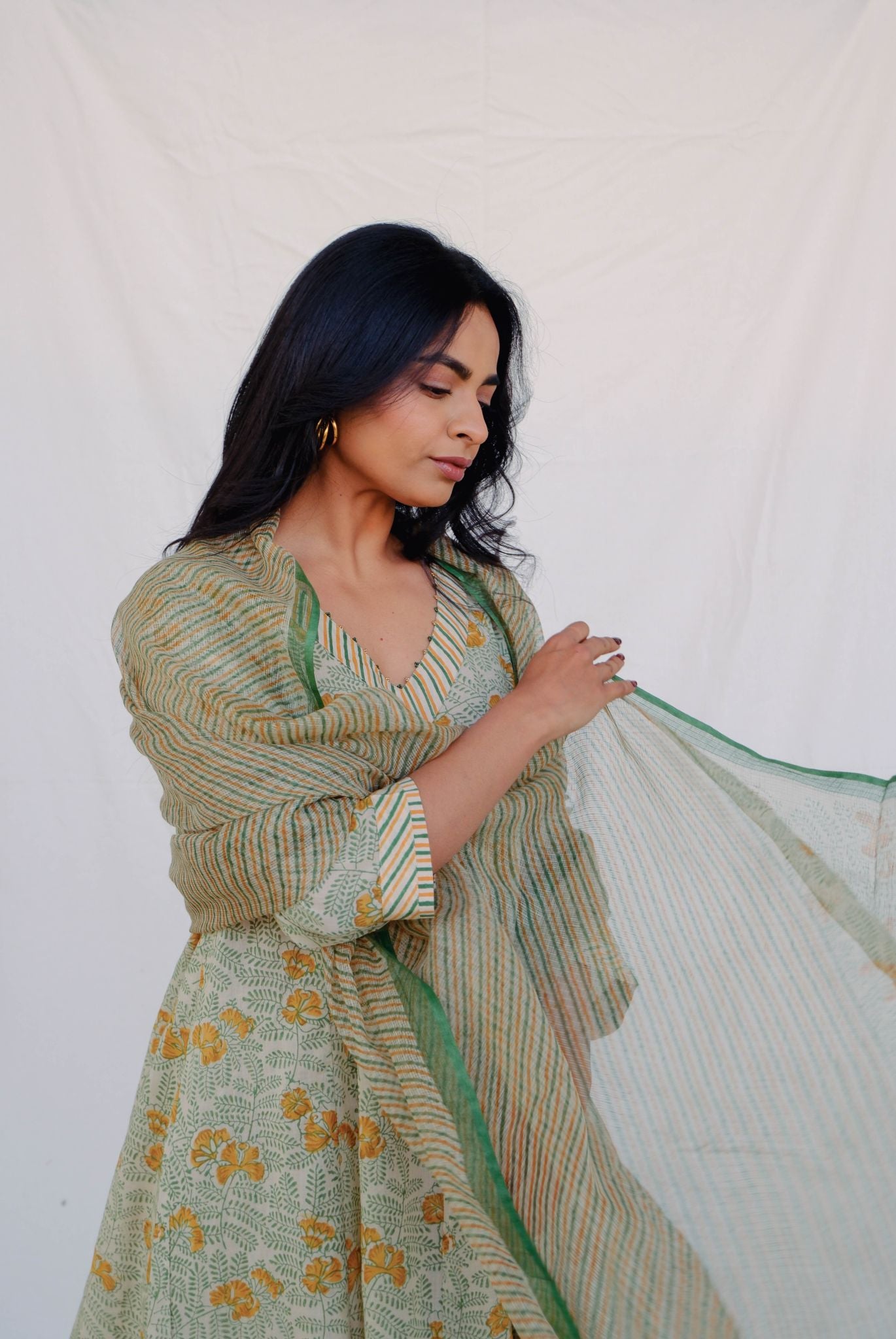 Woman wearing a green floral dress with a matching shawl against a white background
