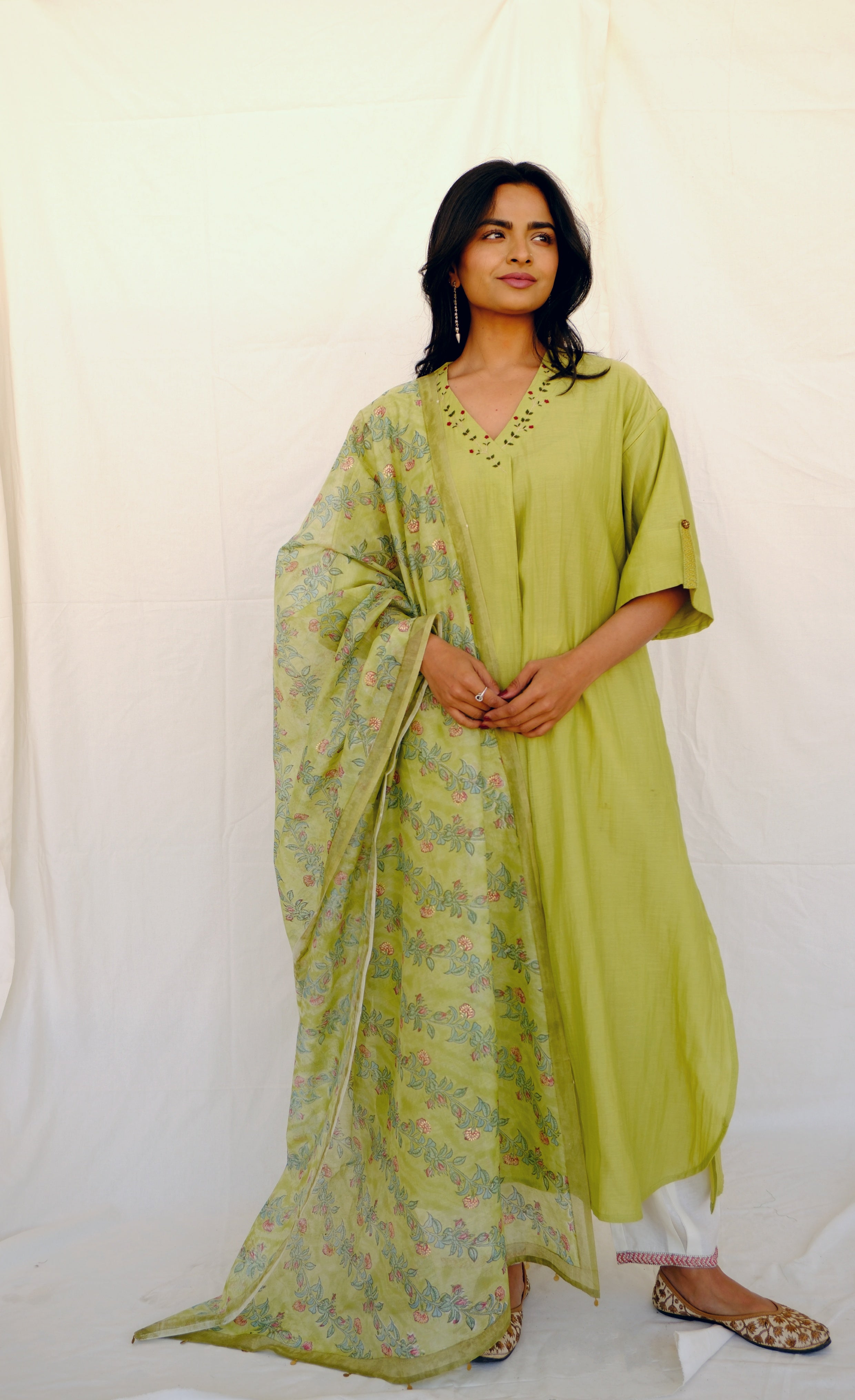 Woman wearing a green kurta with a matching dupatta on a white background