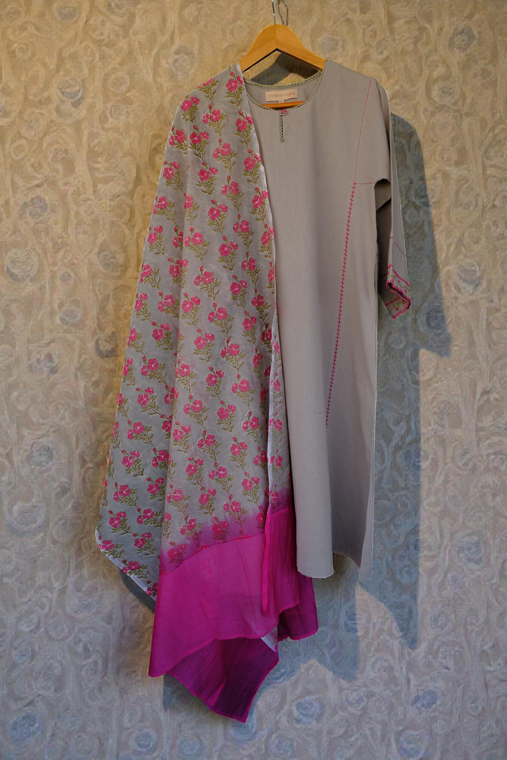 Grey kurta and Dupatta hanging on a patterned wall