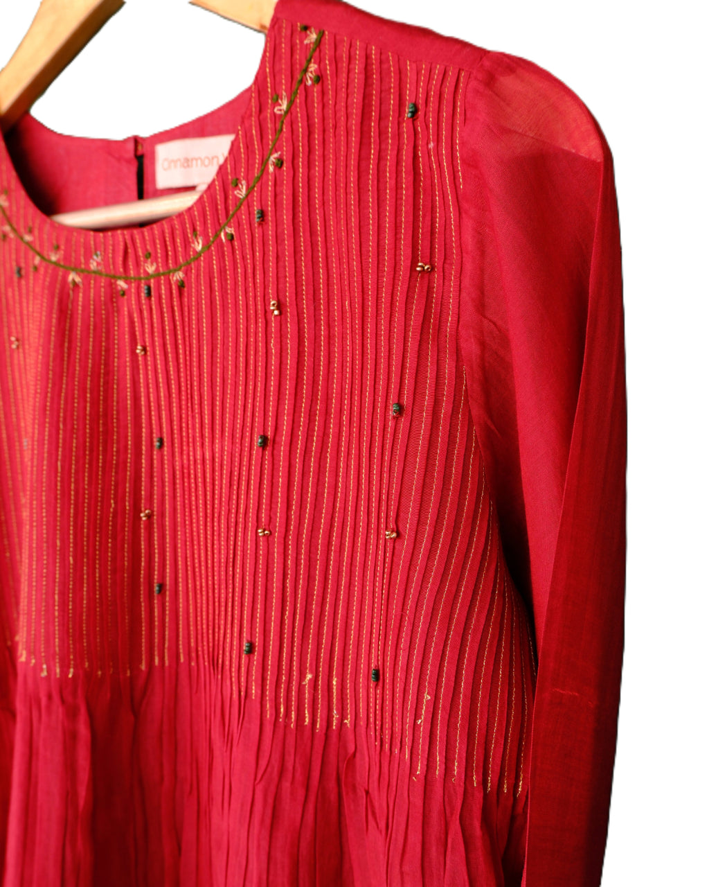 Red blouse with gold embroidery on a wooden hanger