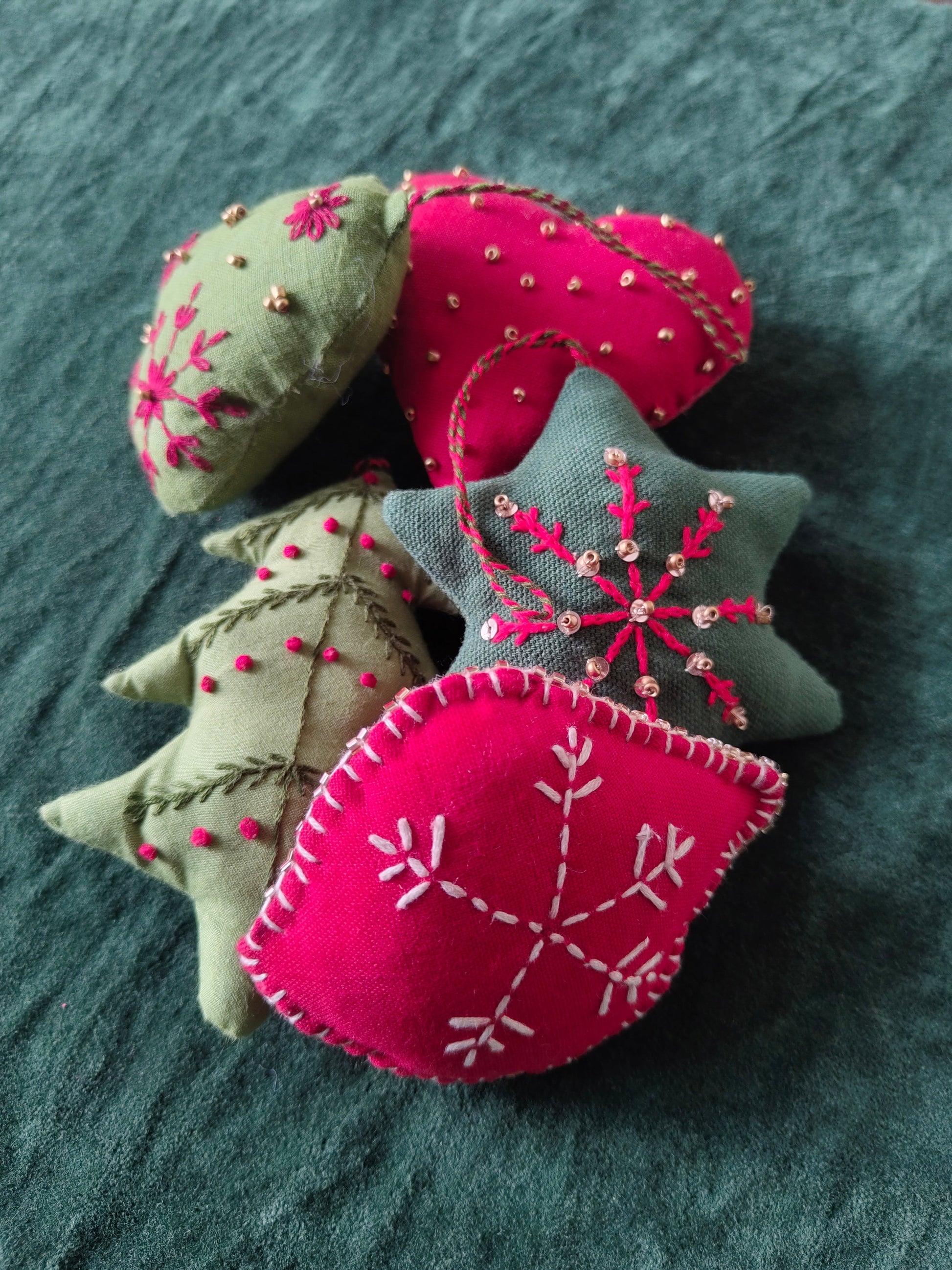 Felt ornaments with embroidered patterns on a textured surface
